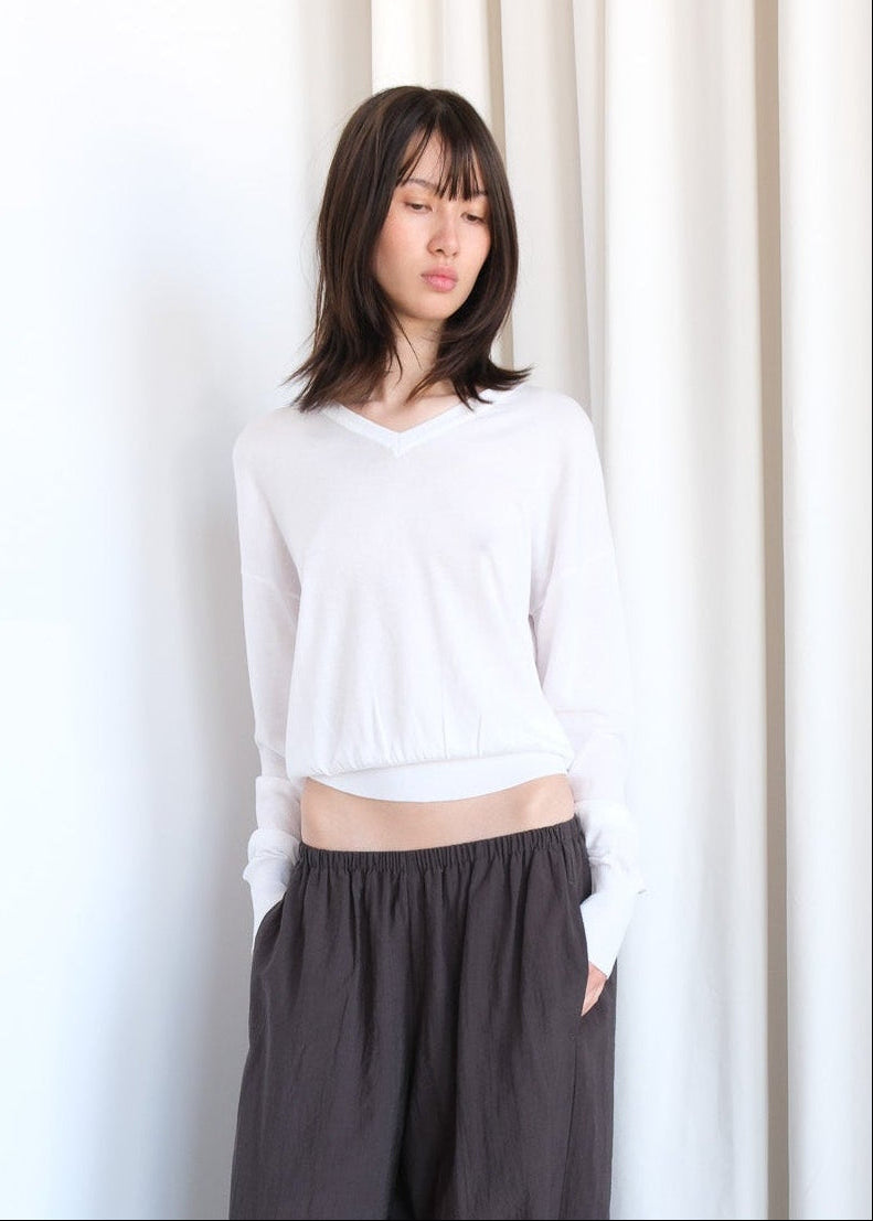 Beige Andrea sweater by geel.us displayed on a hanger, featuring a cozy knit texture and classic crew neckline.