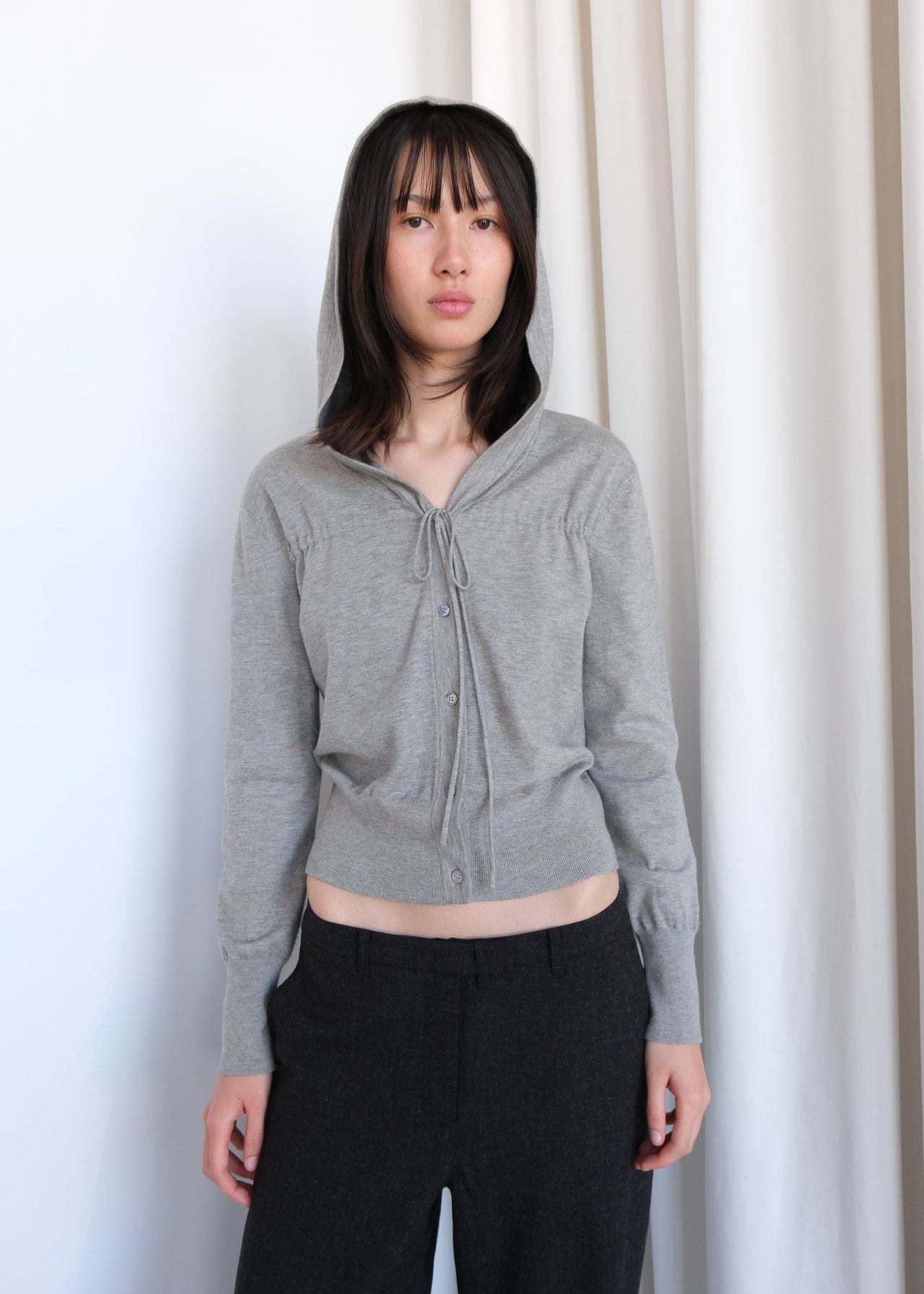 Light gray Rori cardigan by geel.us, shown on a hanger with a soft knit texture and long sleeves, casual and cozy apparel.